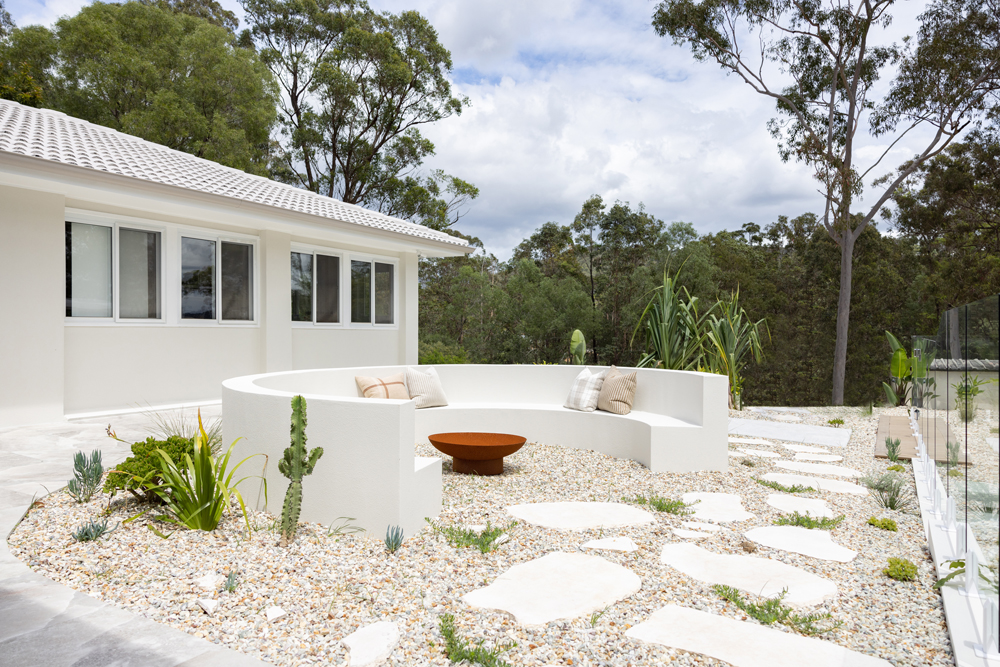 White rendered curved seating around a fire pit in a pebbled garden