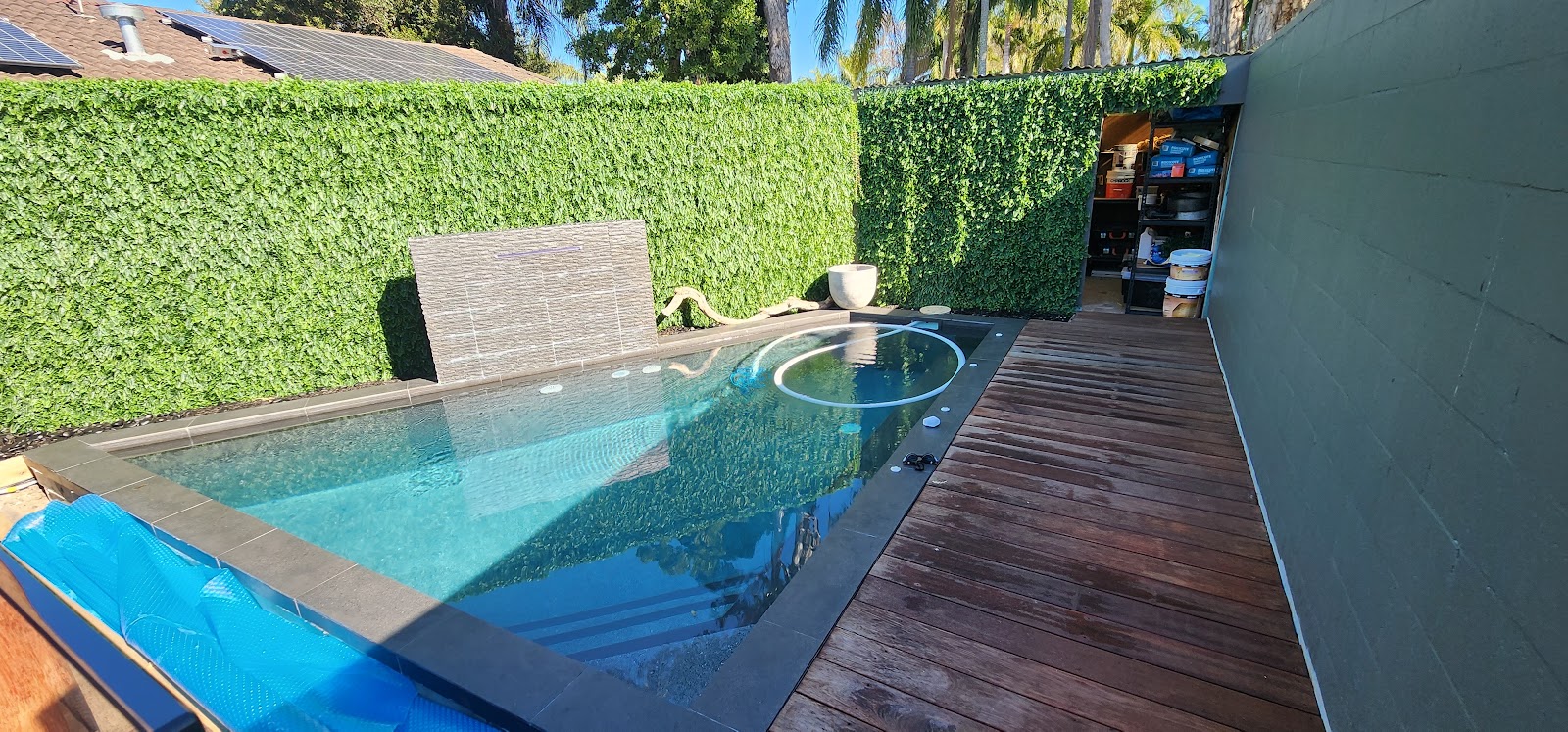 Plunge pool with dark coping beside a timber deck